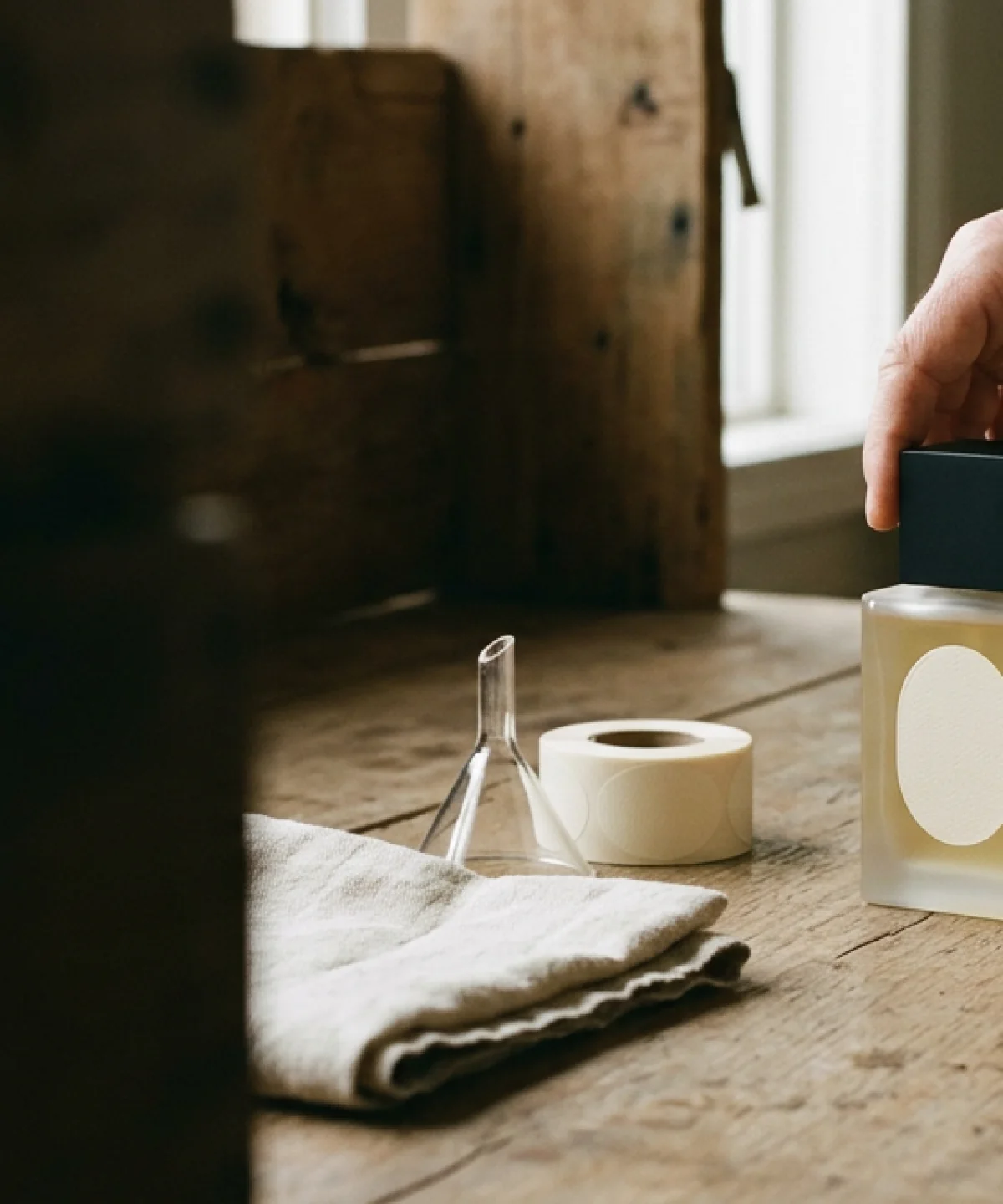 Hands setting a black cap on a freshly filled bottle on a wooden bench
