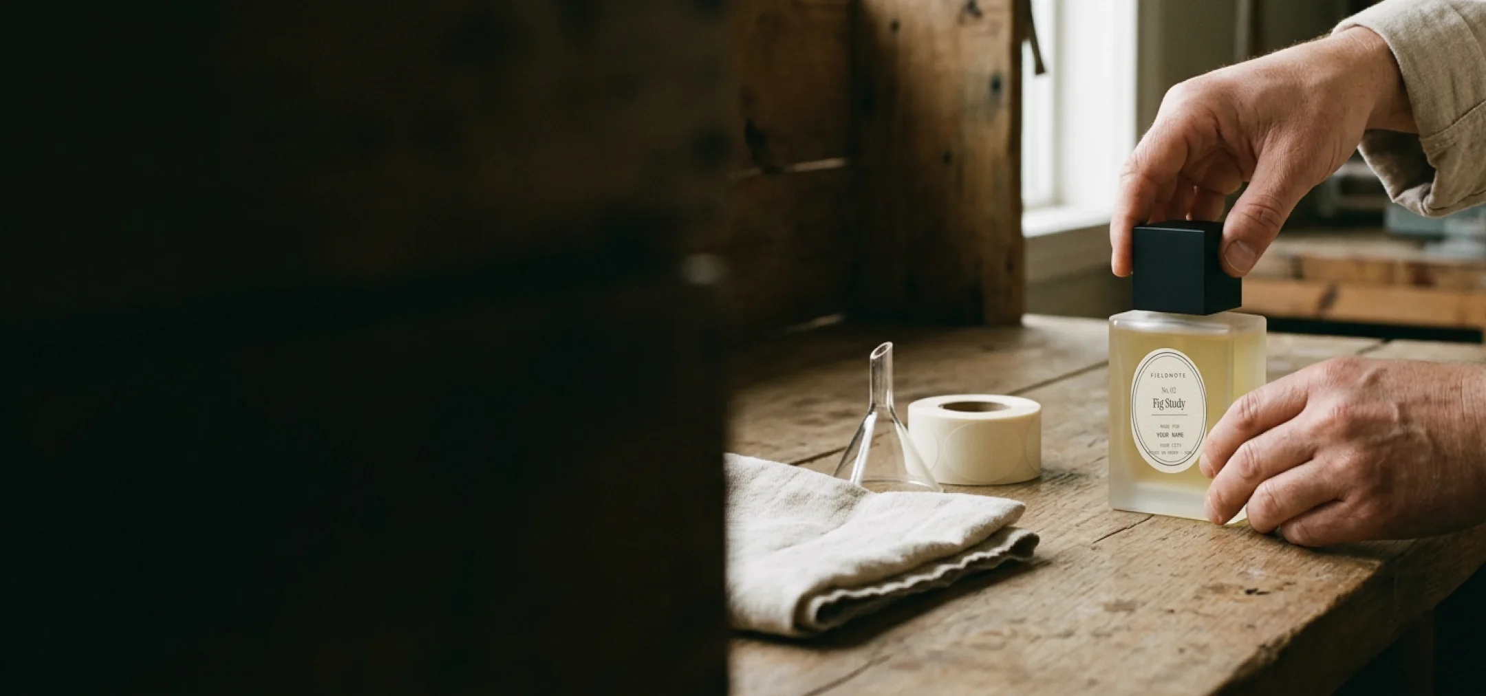 Hands setting the cap on a freshly labeled Fig Study bottle at the workbench